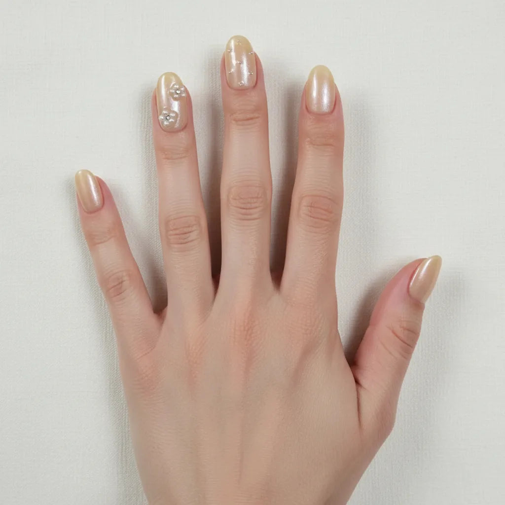 Dorsal view of hand wearing Golden Hour handmade press-on nails — light skin tone, fingers spread wide, short oval champagne nude pearl nails, index finger with delicate silver flower bead cluster, ring finger with scattered silver constellation beads, all nails clearly visible